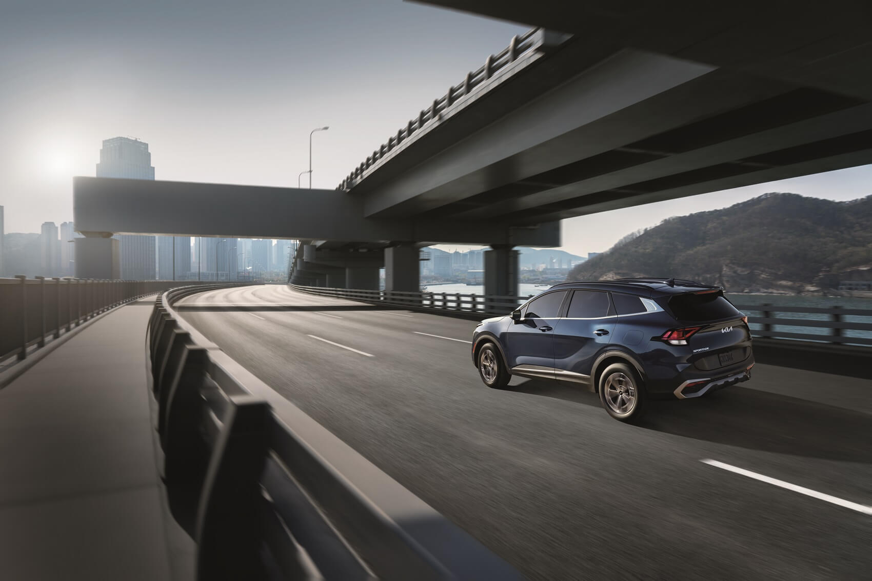 kia sportage driving on highway with city in background